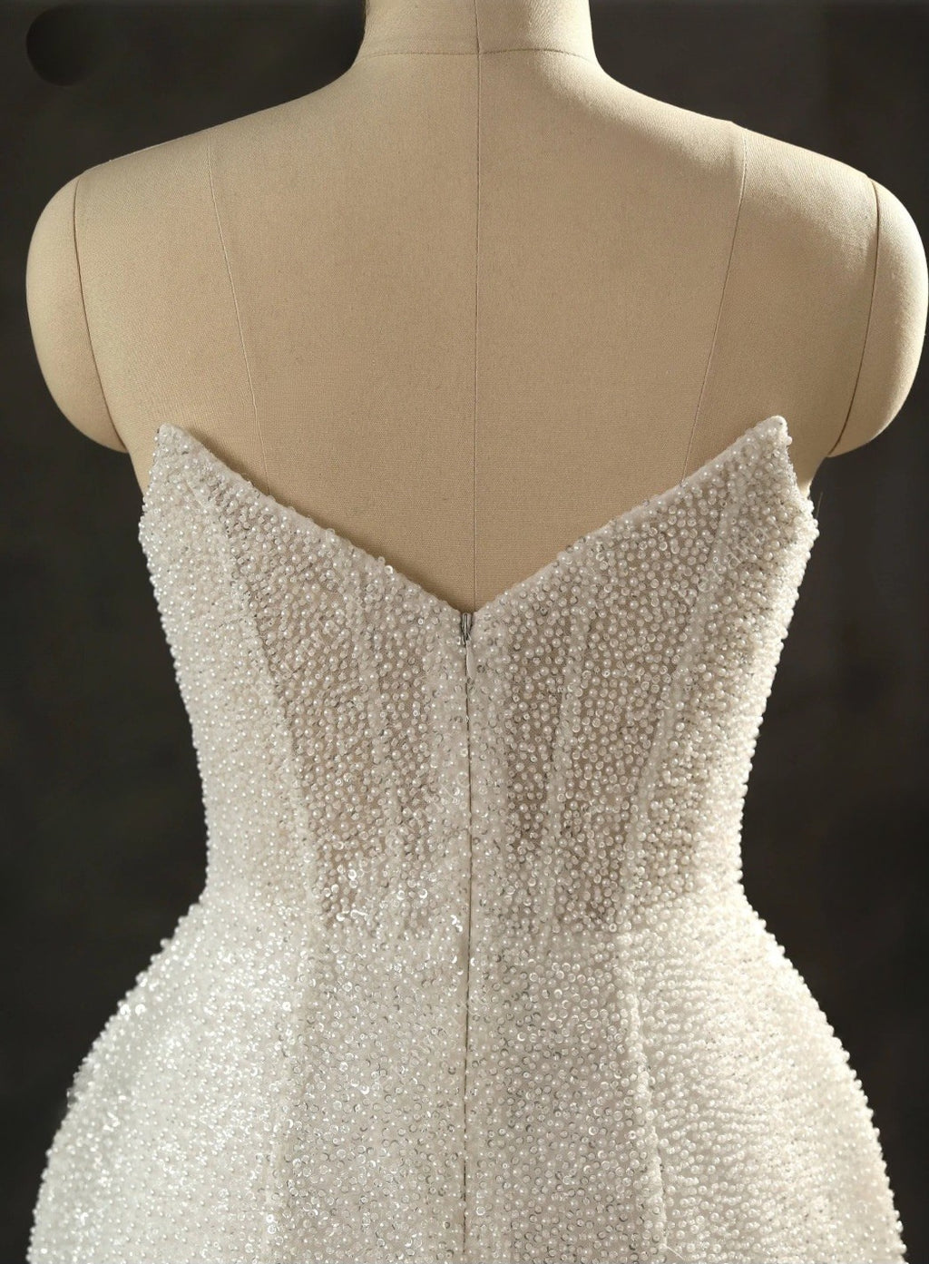 Beaded strapless dress on a mannequin against a dark background
