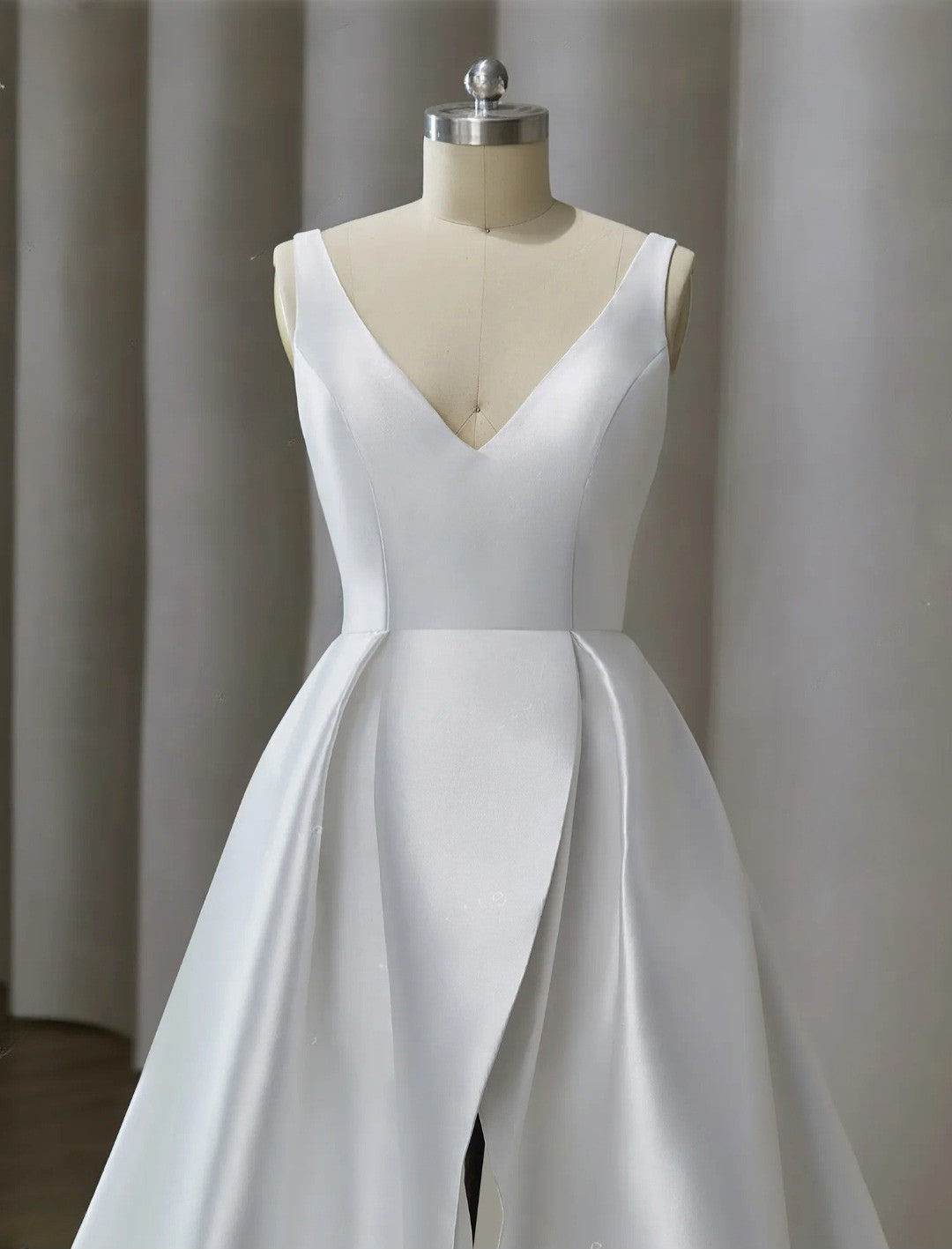 White wedding dress on a mannequin against a plain background