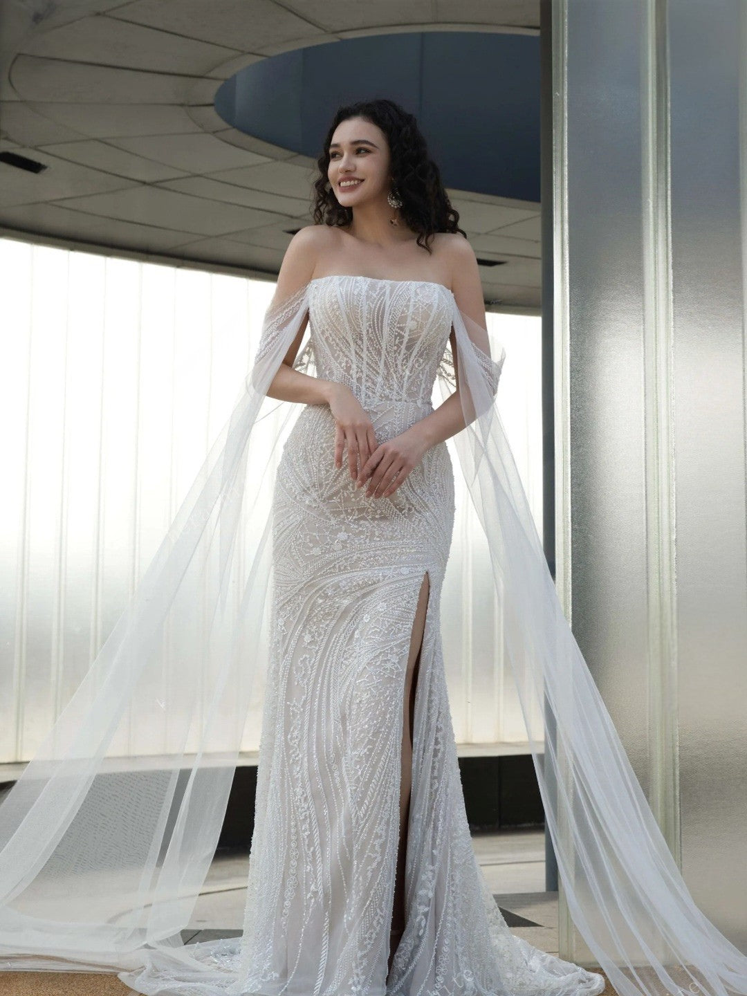 Woman in a white strapless gown with a long train indoors.