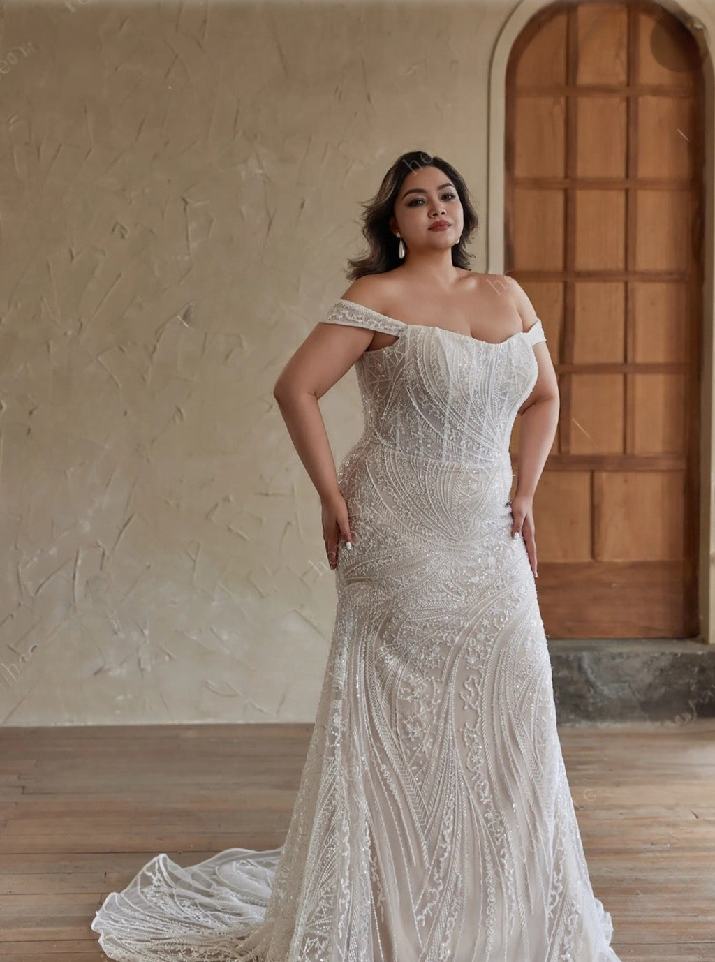 Woman wearing a white lace wedding dress indoors with a neutral background