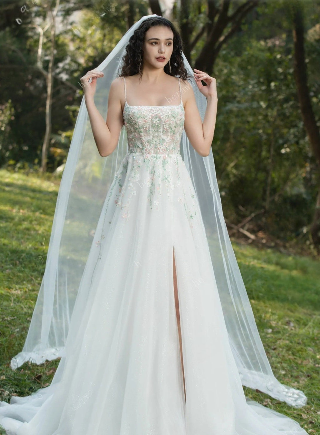 Woman in a wedding dress with a long veil standing outdoors.