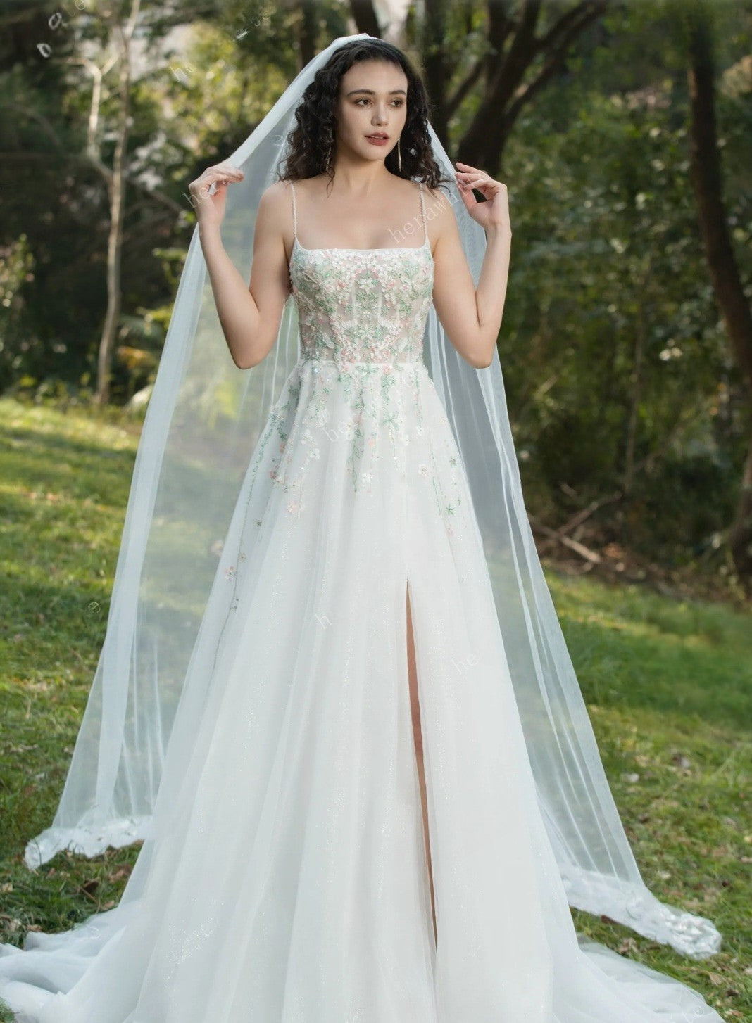 Woman in a wedding dress with a long veil standing outdoors.