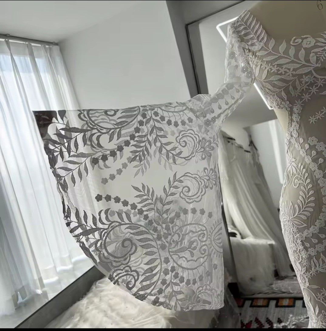 Lace fabric with intricate patterns on a mannequin against a neutral background