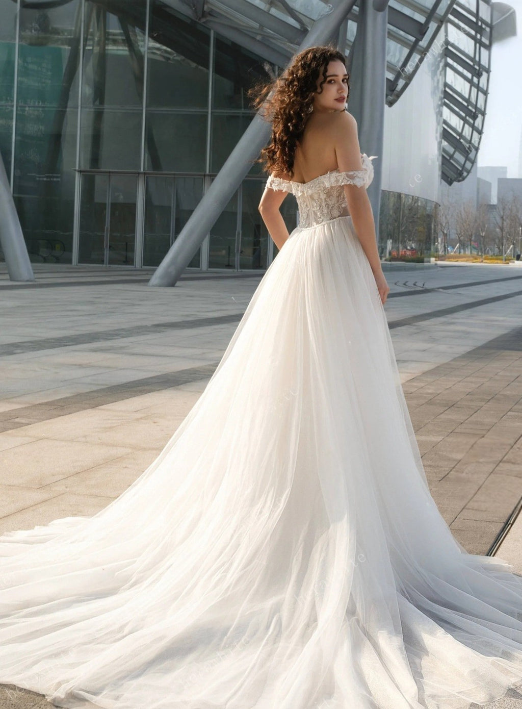 Woman in a white wedding dress standing in an urban setting.