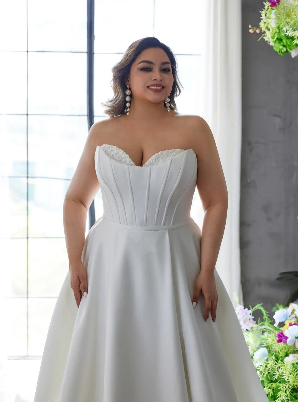 Woman wearing a strapless white wedding dress in a bright indoor setting.