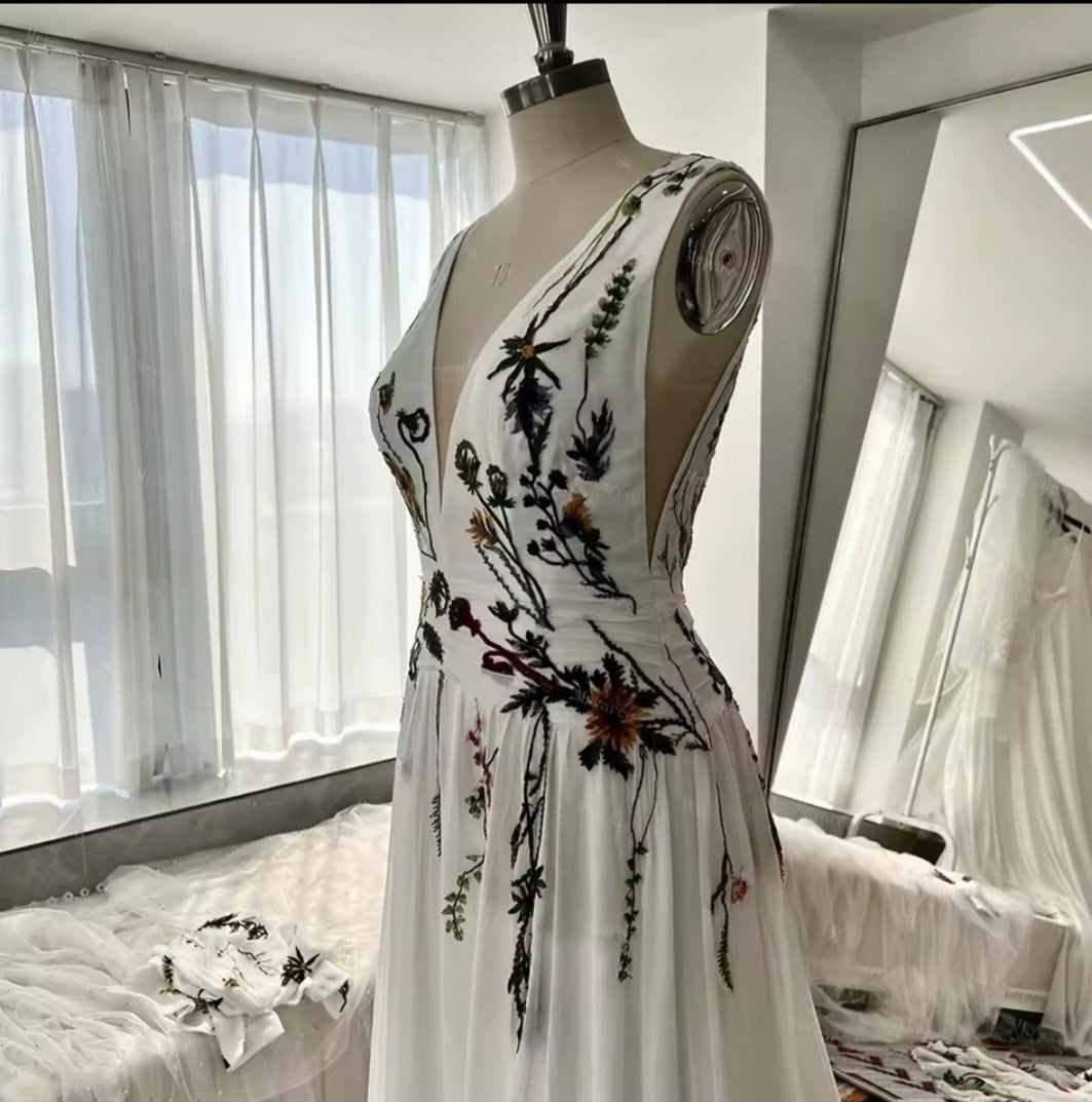 Mannequin wearing a white dress with floral embroidery in a bright room.