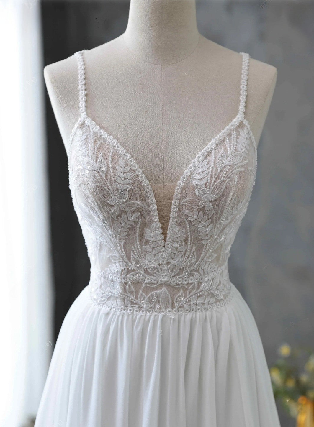 White lace wedding dress on a mannequin against a neutral background