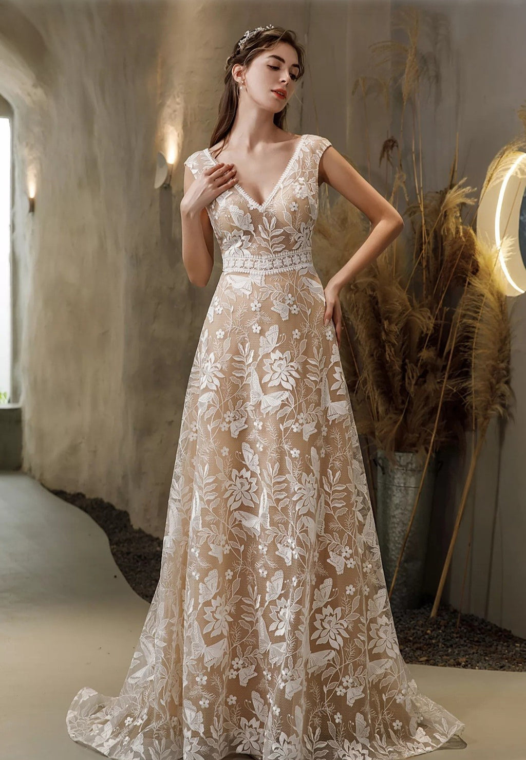 Woman wearing a lace wedding dress in an indoor setting with decorative elements.