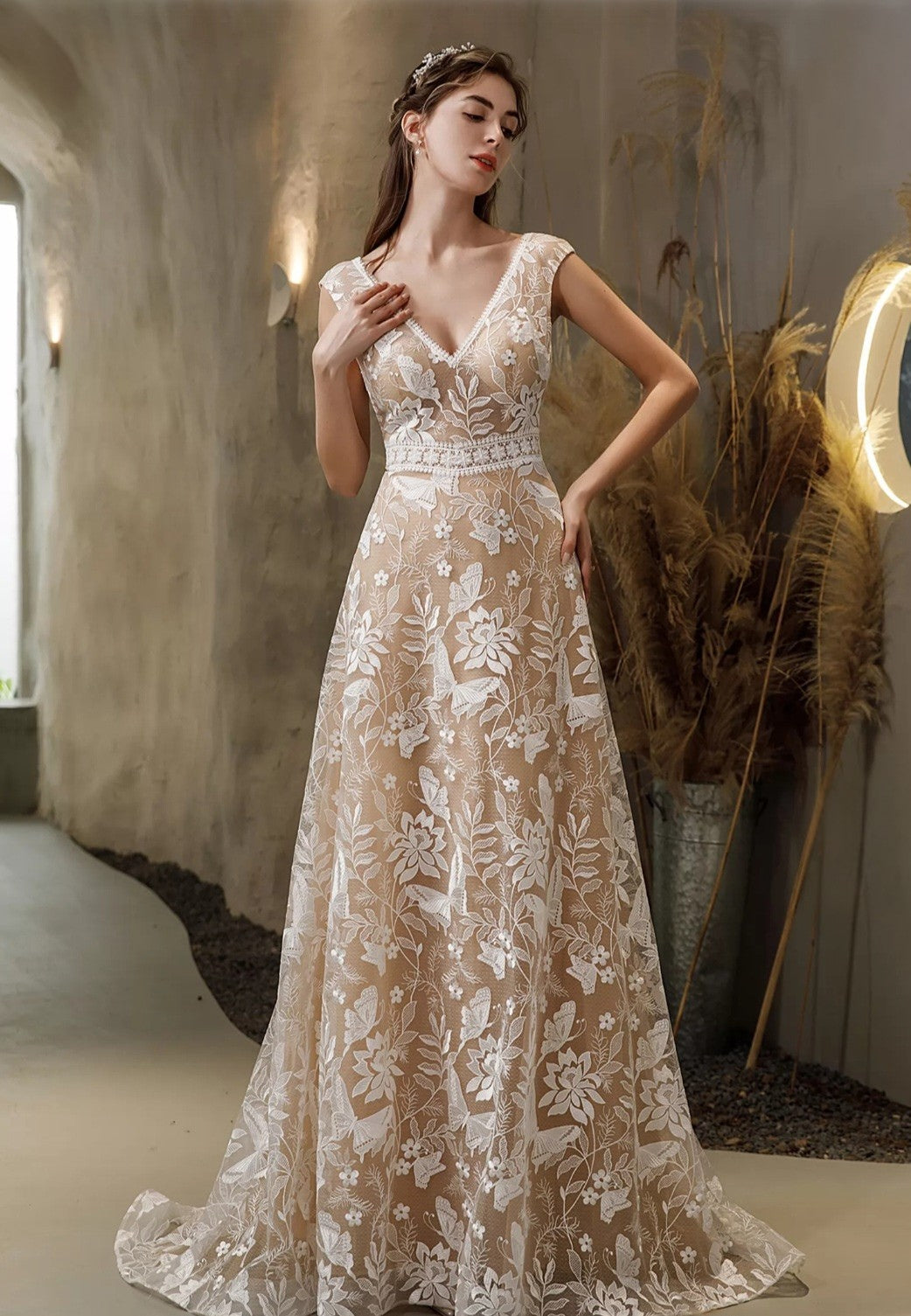 Woman wearing a lace wedding dress in an indoor setting with decorative elements.