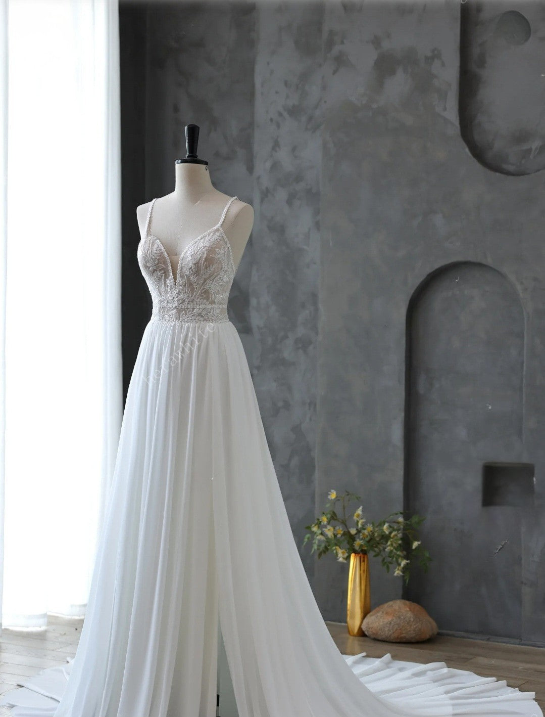 White lace dress on a mannequin against a gray wall with decorative elements.