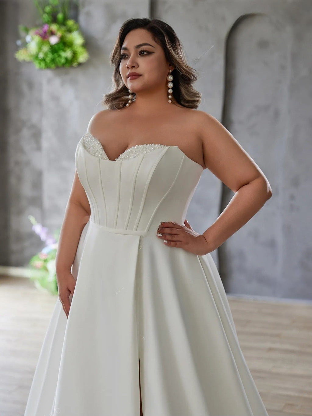 Woman wearing a white strapless dress with a textured bodice in an indoor setting.