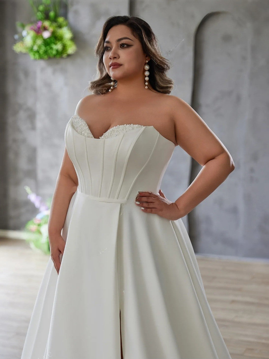Woman wearing a white strapless dress with a textured bodice in an indoor setting.