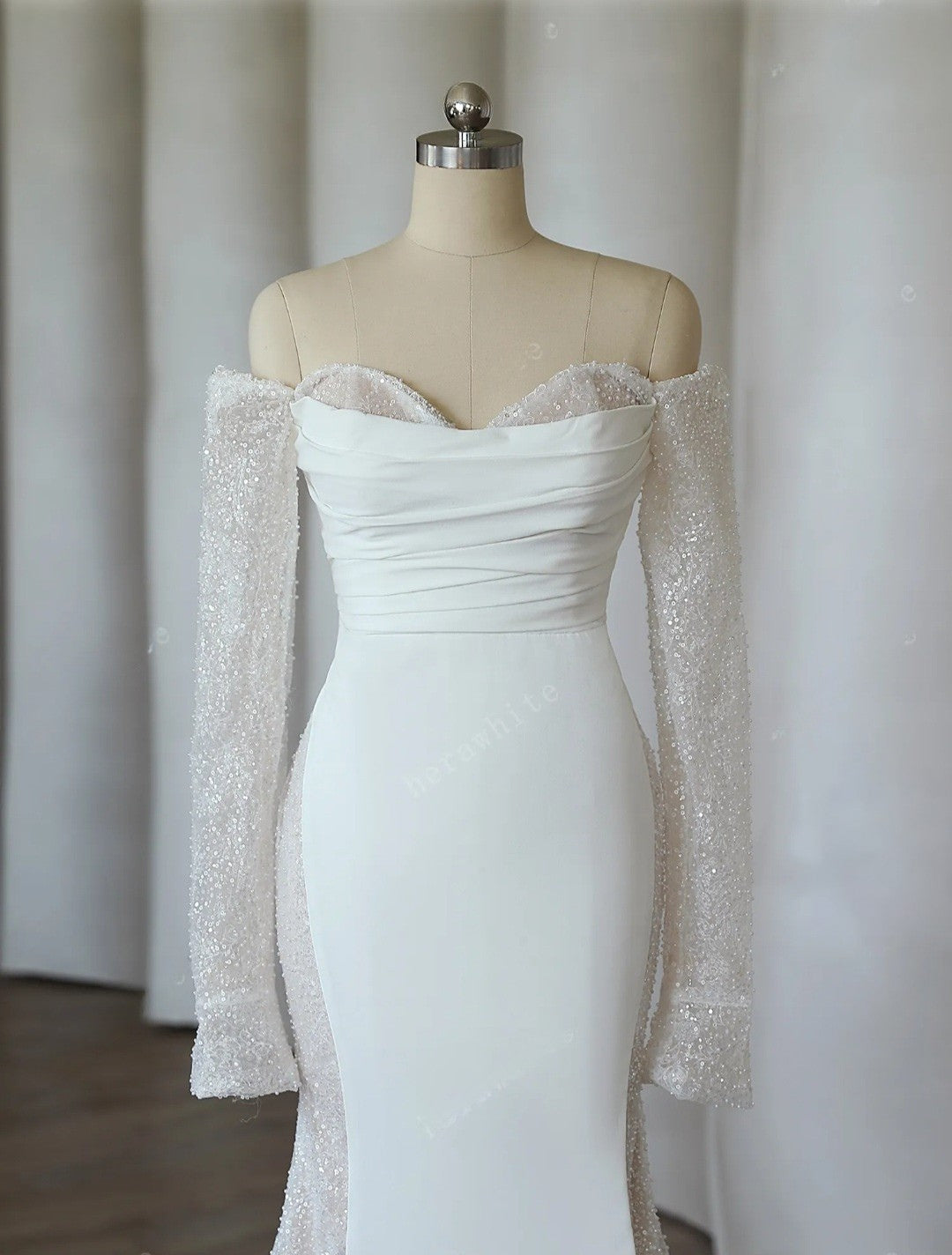 White off-shoulder dress with sheer sleeves on a mannequin against a plain background