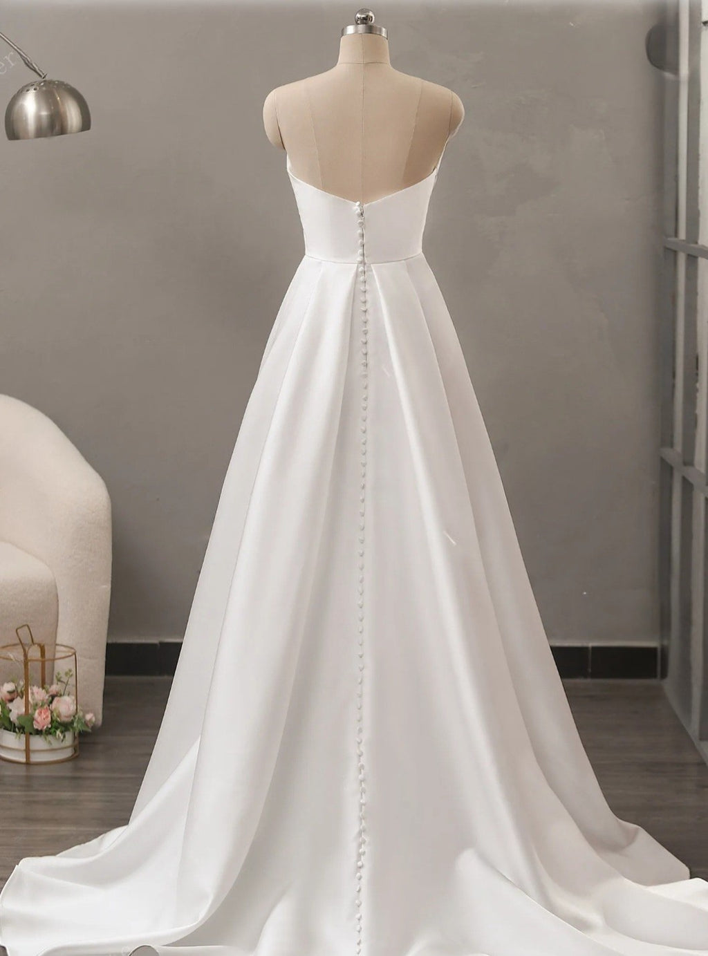 White wedding dress on a mannequin against a neutral background