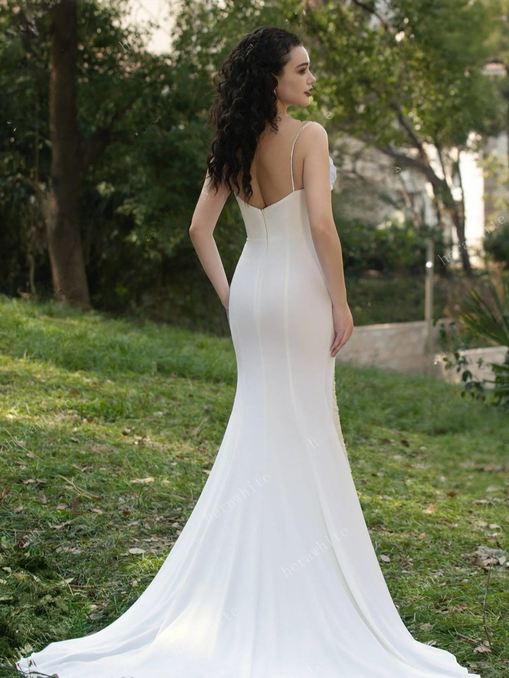 Woman in a white wedding dress standing in a park.