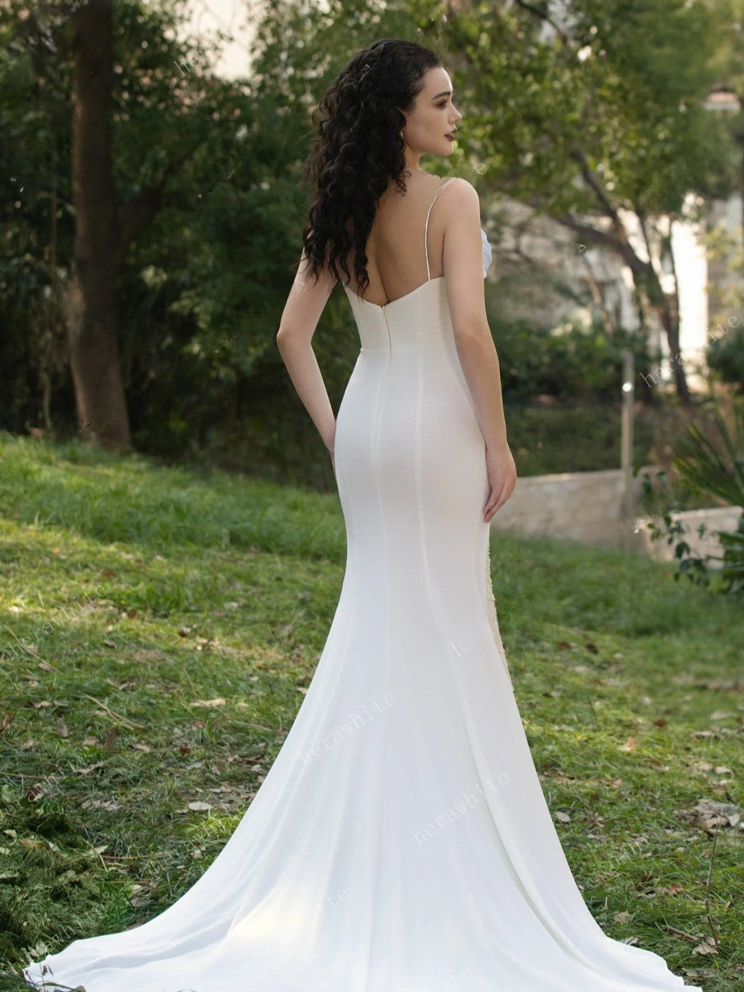 Woman in a white wedding dress standing in a park.