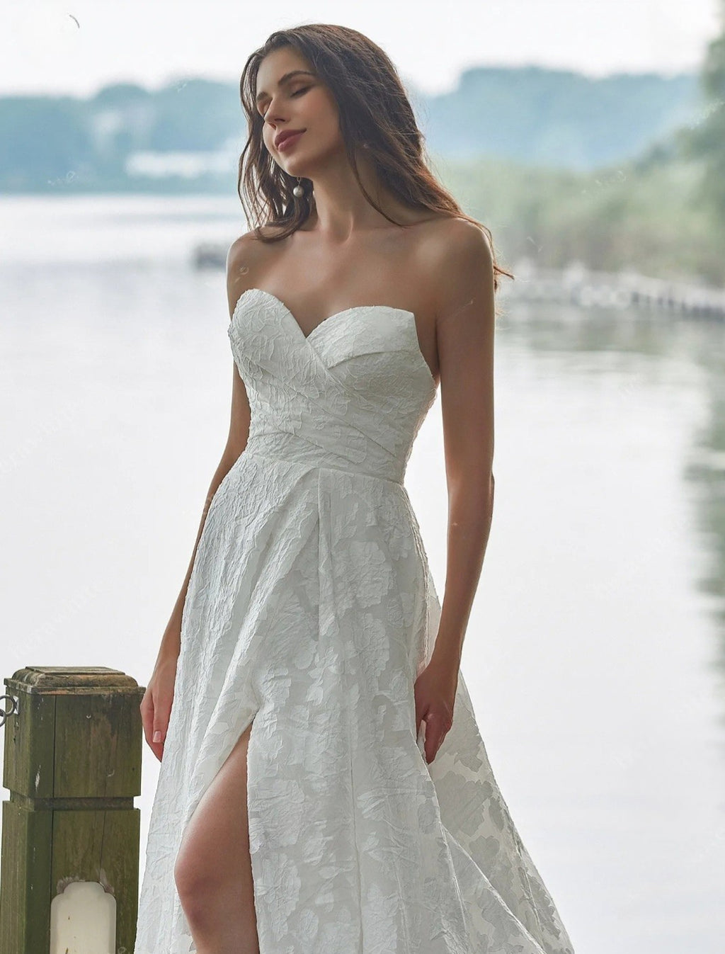 Woman in a white strapless dress standing by a waterfront