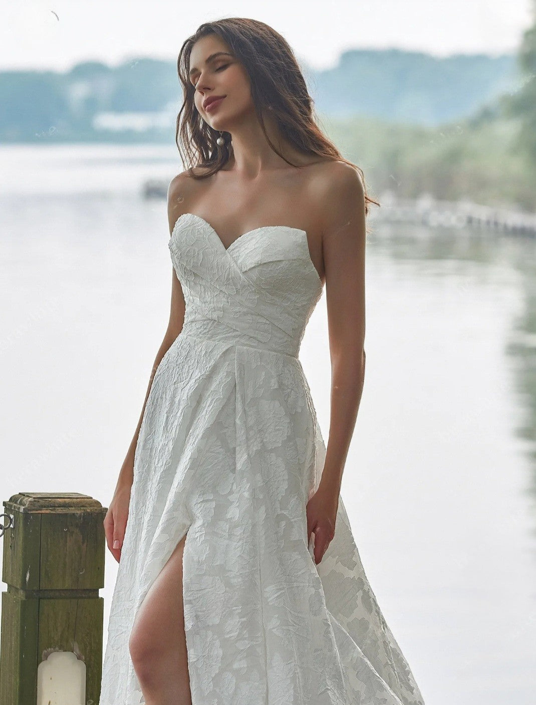 Woman in a white strapless dress standing by a waterfront