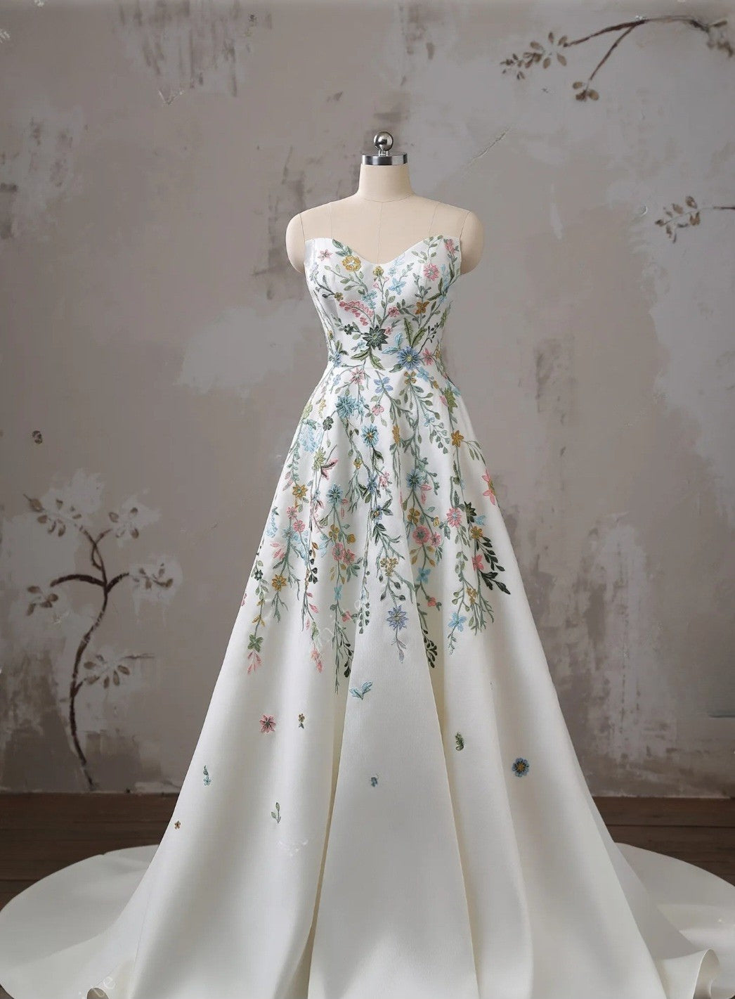 Floral dress on a mannequin against a textured wall.