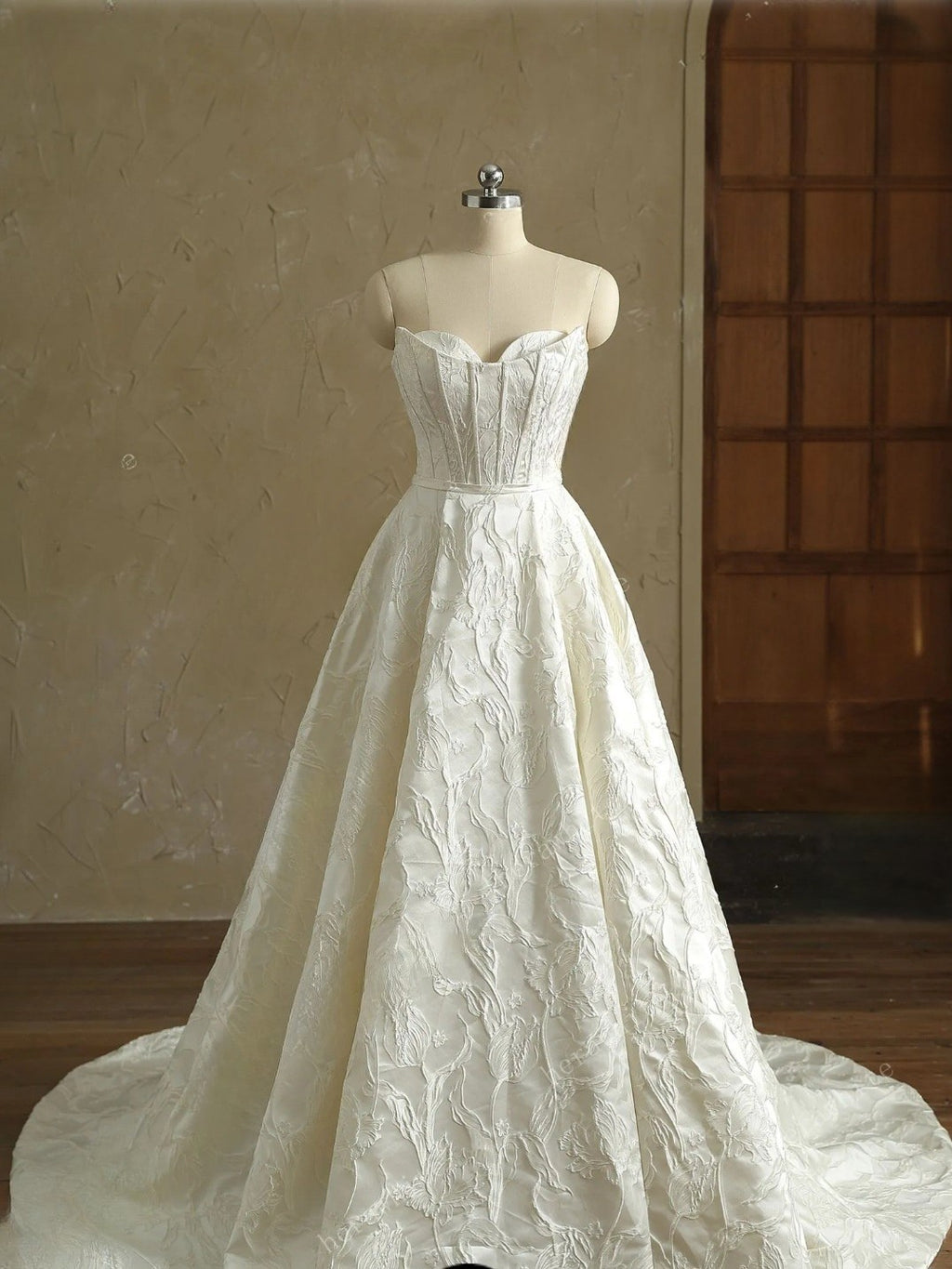 White lace wedding dress on a mannequin against a neutral background
