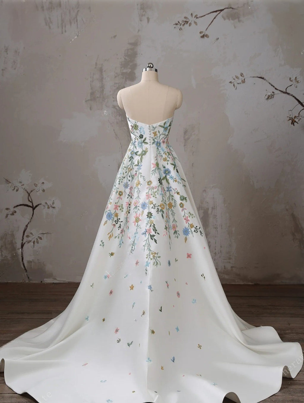 Floral-patterned gown on a mannequin against a textured wall.