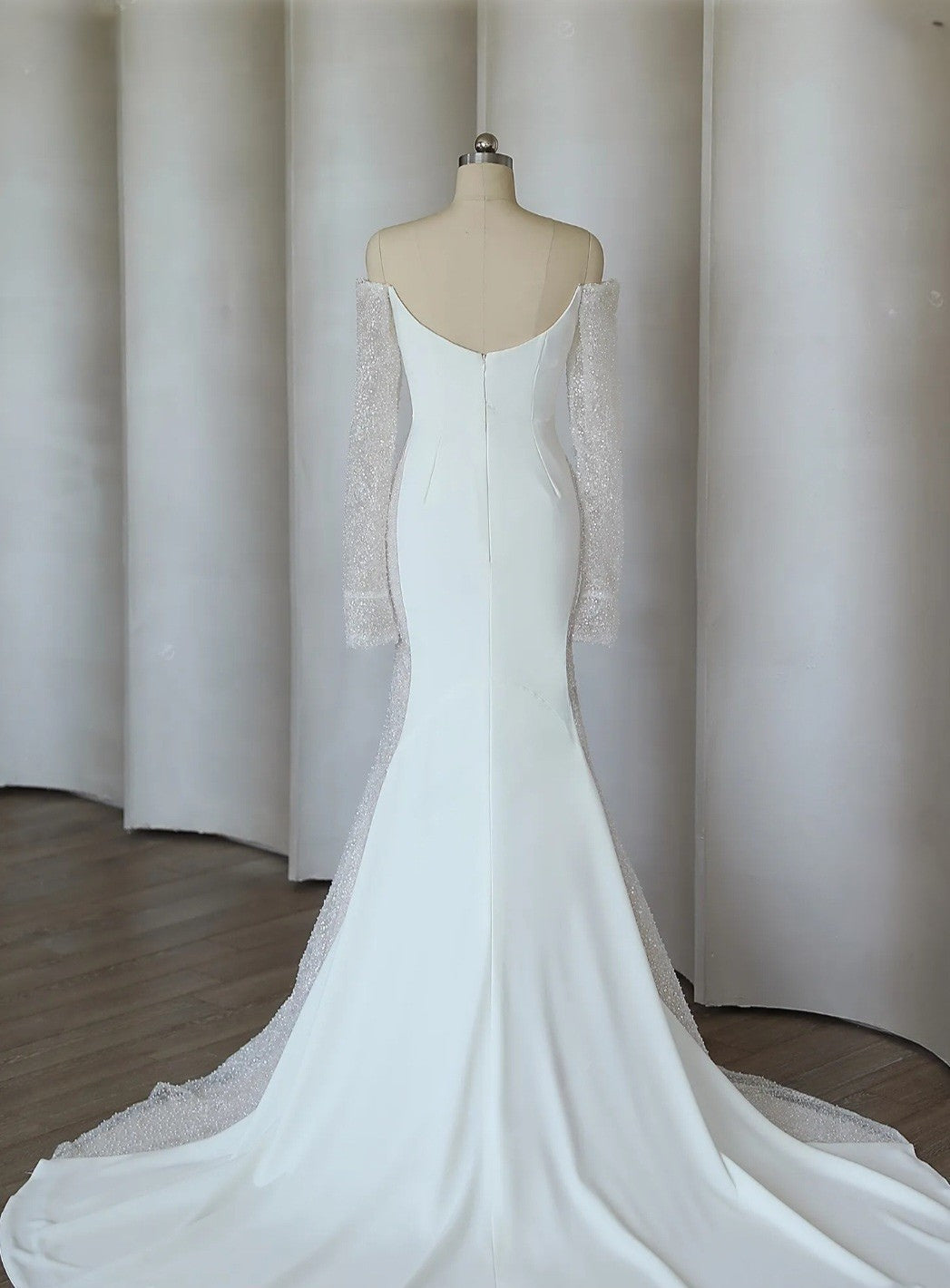 White wedding dress with a sheer shrug on a mannequin against a neutral background
