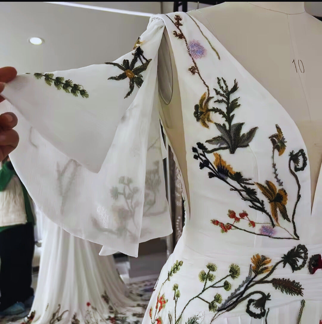 Close-up of a white garment with floral embroidery on a mannequin.