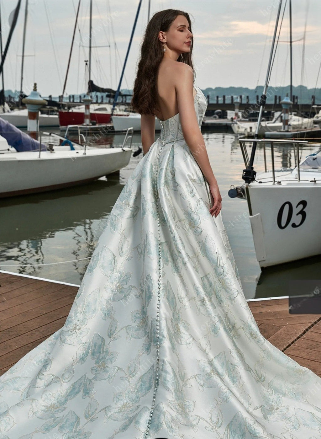 Woman in a strapless gown standing by a marina with boats in the background