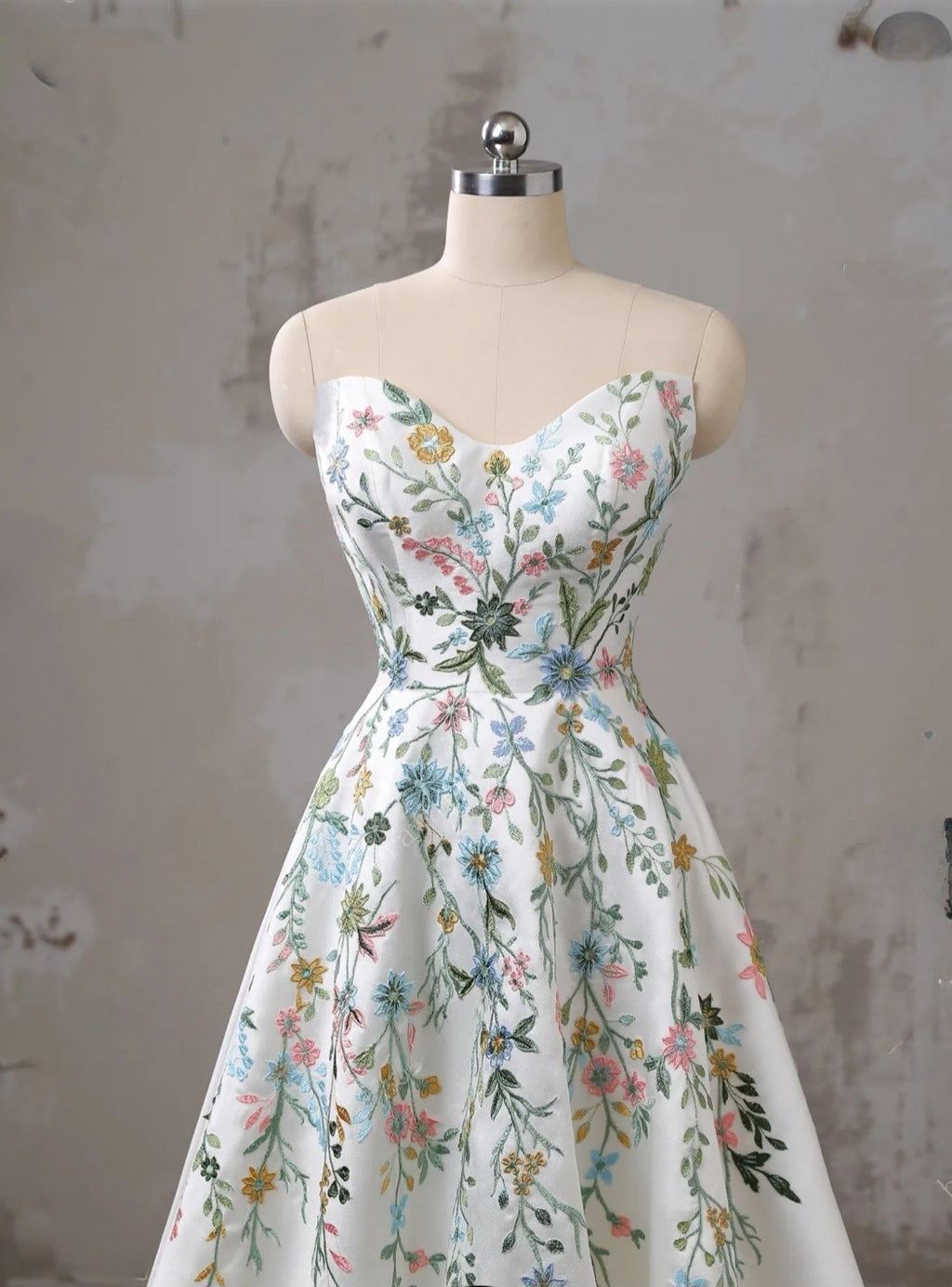 Floral dress on a mannequin against a textured wall.