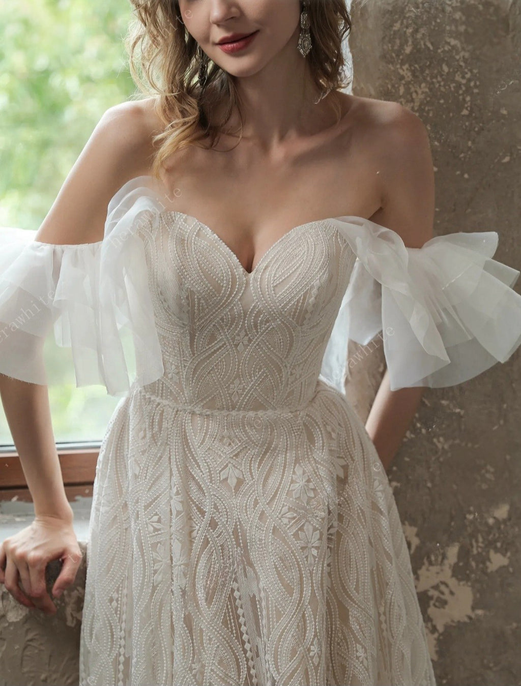 Woman wearing a white lace wedding dress with ruffled sleeves.